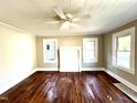 Inviting living room featuring a ceiling fan, wood floors and bright natural light from the windows at 111 113 Highland Ave, Burlington, NC 27217