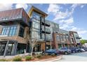 Modern building exterior with a mix of brick, wood, and glass, plus ample parking and manicured landscaping at 120 Mosaic Blvd # 308, Pittsboro, NC 27312