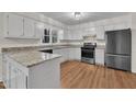 Bright kitchen featuring white cabinets, granite countertops, and stainless steel appliances, creating a modern cooking space at 122 Monticello Ave, Durham, NC 27707