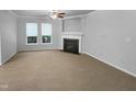 A spacious living room with neutral walls, carpet, a fireplace, and large windows offering natural light at 1412 Wesser Ct, Fuquay Varina, NC 27526