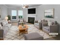 Bright living room featuring a cozy fireplace, plush seating, and natural light from large windows at 1412 Wesser Ct, Fuquay Varina, NC 27526
