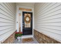 Inviting front door with a decorative wreath, colorful rug, and flower pot accents at 184 Wildfell Trl, Cary, NC 27513