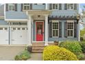 Home featuring a bright red front door, black shutters, and a three-car garage on a sunny day at 200 Windy Knoll Cir, Chapel Hill, NC 27516