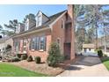 A beautifully landscaped side view of the home showcasing a brick chimney and mature trees at 228 Old Colony Way, Rocky Mount, NC 27804