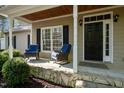 Inviting front porch with rocking chairs, stone base, and a dark front door at 359 Punch Hill Farm Rd, Rougemont, NC 27572