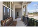 Relaxing front porch with a wooden bench, stone pillars, and black railing at 437 Creekhurst Pl, Cary, NC 27519
