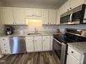 Updated kitchen with stainless steel appliances, granite countertops, white cabinets, and wood flooring at 46 Grain Ln, Henderson, NC 27537