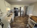 Modern kitchen with stainless steel appliances, granite countertops, white cabinets, and wood flooring at 46 Grain Ln, Henderson, NC 27537