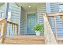 A welcoming blue front door with wooden railing and a potted fern, offering a cozy entrance at 505 Marion Way, Chapel Hill, NC 27516