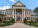 Close up of a beautiful brick home showcasing grand columns and meticulously maintained landscaping at 5768 Cavanaugh Dr, Raleigh, NC 27614
