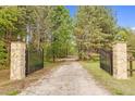 Grand entrance with stone pillars and iron gates, leading to a private drive, providing security and a touch of elegance at 93 Clifton Pond Rd, Louisburg, NC 27549