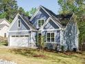 Charming blue home featuring stone accents, an attached garage, and a well-manicured lawn at 113 Tower Ridge Ln, Sanford, NC 27330
