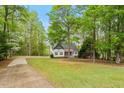 Scenic view of home nestled among mature trees and a lush green lawn with a long driveway at 147 W Alex Dr, Clayton, NC 27520