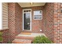 Welcoming brick front porch with a storm door entry, decorative window, and charming landscaping at 1515 Poets Glade Dr, Apex, NC 27523