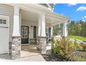Inviting covered front porch with stone-clad columns and outdoor seating area at 1725 Langlais Dr, Graham, NC 27253