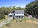 Expansive view of a charming home with lush greenery, a detached garage, and well-manicured landscaping at 230 Bradley Dr, Benson, NC 27504
