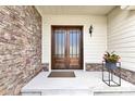 A warm, inviting front porch featuring a wood double door, stone accents, and decorative plants at 2613 Beckwith Rd, Apex, NC 27523