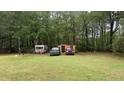 Wide backyard with plentiful foliage, a trailer, storage shed and two pickup trucks at 300 E Vance St, Zebulon, NC 27597