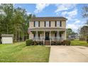 Charming home featuring a cozy front porch, well-maintained landscaping, and a welcoming American flag at 34 Stuart Dr, Benson, NC 27504
