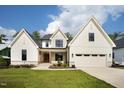 Attractive two-story home boasting a modern white facade, stone accents, and a green lawn at 3832 Noremac Dr, Raleigh, NC 27612