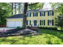 Two-story yellow home with a two-car garage and landscaped front yard with mature tree at 3900 Inkberry Ct, Apex, NC 27539