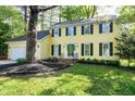 Charming two-story yellow home with black shutters surrounded by lush green lawn and trees at 3900 Inkberry Ct, Apex, NC 27539