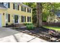 Two-story yellow home featuring a landscaped front yard with flowers and rock borders at 3900 Inkberry Ct, Apex, NC 27539