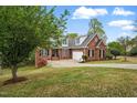 A charming red brick home with attached garage, set on a well-maintained sloping lawn at 48 Arabella Ln, Clayton, NC 27520