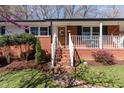 Inviting brick front porch with white railings and stairs leading to a wood front door with wreath at 5033 Green Oak Dr, Durham, NC 27712