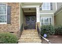 Close-up of a home's entrance featuring stone accents, a double front door with wreaths, and manicured landscaping at 515 Bexley Bluff Ln, Cary, NC 27513