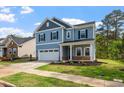 Two-story blue home with a two-car garage and a cozy front porch nestled in a landscaped neighborhood at 5209 Woodlawn Dr, Durham, NC 27703