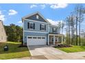 Two-story home with blue siding, black shutters, a well-manicured lawn, and a two-car garage at 5209 Woodlawn Dr, Durham, NC 27703