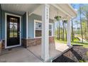 Close-up of the home's entrance with a charming porch, decorative plants, and stone accents at 5209 Woodlawn Dr, Durham, NC 27703
