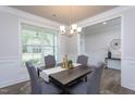 Formal dining room featuring modern decor, a chandelier, gray chairs, and plenty of natural light at 108 Pronghorn Deer Ct, Garner, NC 27529