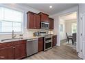 Modern kitchen with stainless steel appliances, granite countertops, and rich wood cabinetry at 108 Pronghorn Deer Ct, Garner, NC 27529