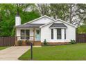 Charming white cottage-style home featuring a cozy porch and well-manicured lawn at 120 Cabrita Ct, Holly Springs, NC 27540