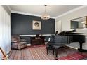Cozy living room showcasing dark accent wall, a piano, area rug, and chair at 1310 Country Club Dr, Durham, NC 27712