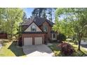 An aerial view of a well-maintained brick home with a two-car garage surrounded by mature trees at 132 Wheatsbury Dr, Cary, NC 27513