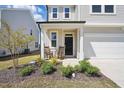 Inviting front porch with rocking chairs, landscaping, and a black front door at 1227 at 135 Carlton Ln, Franklinton, NC 27525