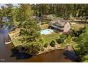 A captivating aerial view of an estate on a lake with a pool, manicured lawn, and mature trees at 1422 Gormly Cir, Sanford, NC 27330