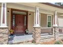 Inviting front porch with stone accents, decorative columns, and a stylish front door at 1422 Gormly Cir, Sanford, NC 27330