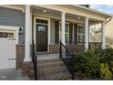 Inviting front porch with brick base columns and black metal railings leading to the front door at 1840 Flint Valley Ln, Apex, NC 27502