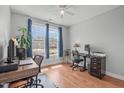 Bright office with hardwood floors, a ceiling fan, two large desks, and large windows with blue curtains at 232 Vinewood Pl, Holly Springs, NC 27540