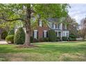 Landscaped front yard featuring a beautiful two-story home with black shutters and mature trees at 2404 Gillingham Dr, Apex, NC 27539