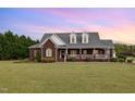 Inviting brick home showcasing a spacious front lawn and a welcoming porch, perfect for relaxing evenings at 495 Evans Rd, Princeton, NC 27569