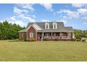 Beautiful brick home with a classic design, expansive lawn, and inviting front porch with white railing at 495 Evans Rd, Princeton, NC 27569