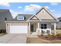 Charming single Gathering home with a two-car garage, stone accents, and cozy front porch with seating at 517 Edenfield Dr, Fuquay Varina, NC 27526