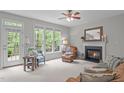 Bright living room featuring a fireplace, ceiling fan, large windows, and access to outdoor deck at 5405 Whisperwood Dr, Durham, NC 27713