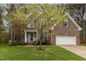 Charming brick home featuring a manicured front lawn, two-car garage and mature landscaping at 8 Queensland Ct, Durham, NC 27712