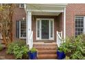 Close-up of a brick front porch with white railings, plants, and a glass front door at 8 Queensland Ct, Durham, NC 27712
